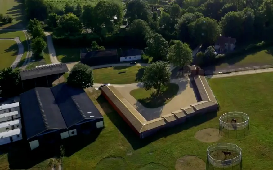 Aerial view of the two large American-style stable barns beside the courtyard yard and horse walkers